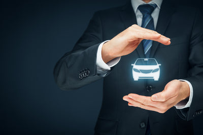 Homme en costume protégeant un hologramme de voiture pour illustrer la garantie auto