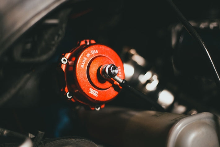 Détail d un capteur de pression et d une wastegate de turbo rouge installés sur un moteur