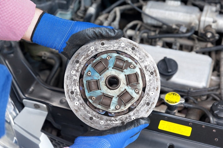 Mécanicien avec gants de protection présentant un disque d embrayage de voiture usé