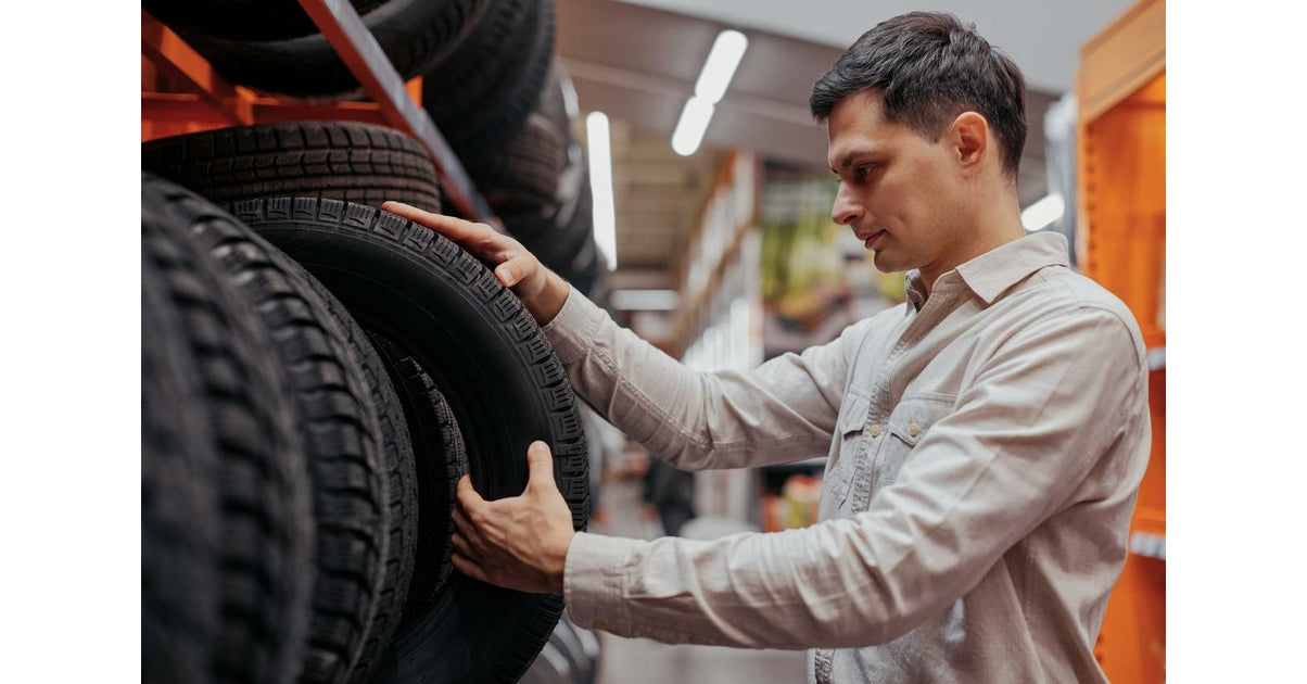 Homme choisissant un pneu de voiture dans un magasin d outillage automobile