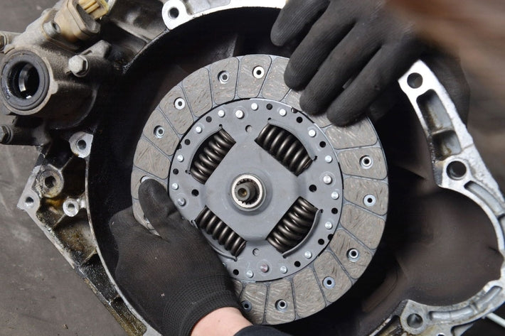 Mains d un mecanicien auto installant un disque d embrayage neuf sur une voiture