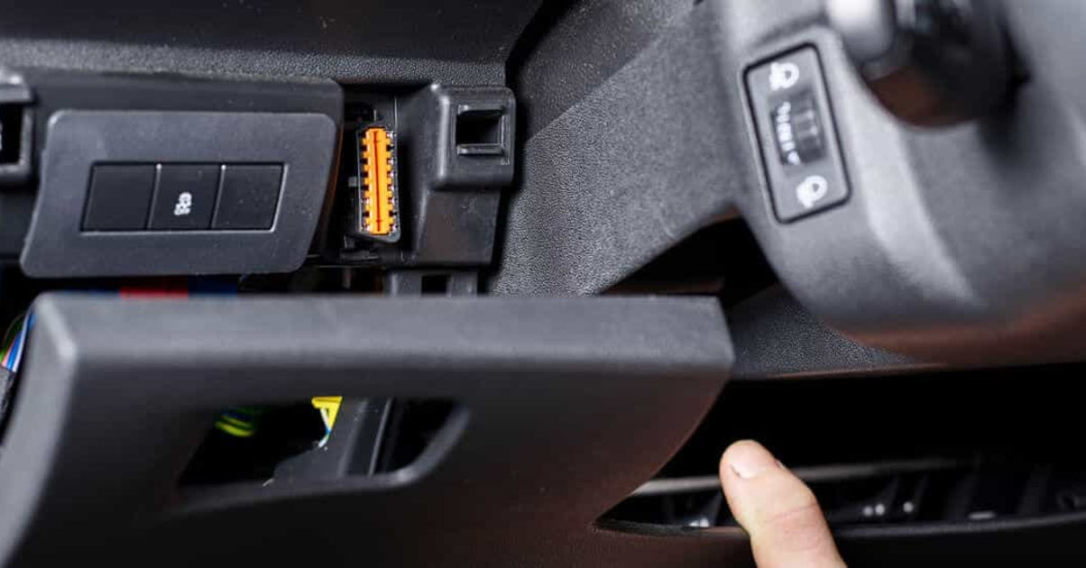 Localisation de la prise de diagnostic OBD2 orange sous le tableau de bord d'un véhicule