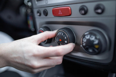 Main réglant le bouton rotatif de la climatisation et du chauffage d'une voiture