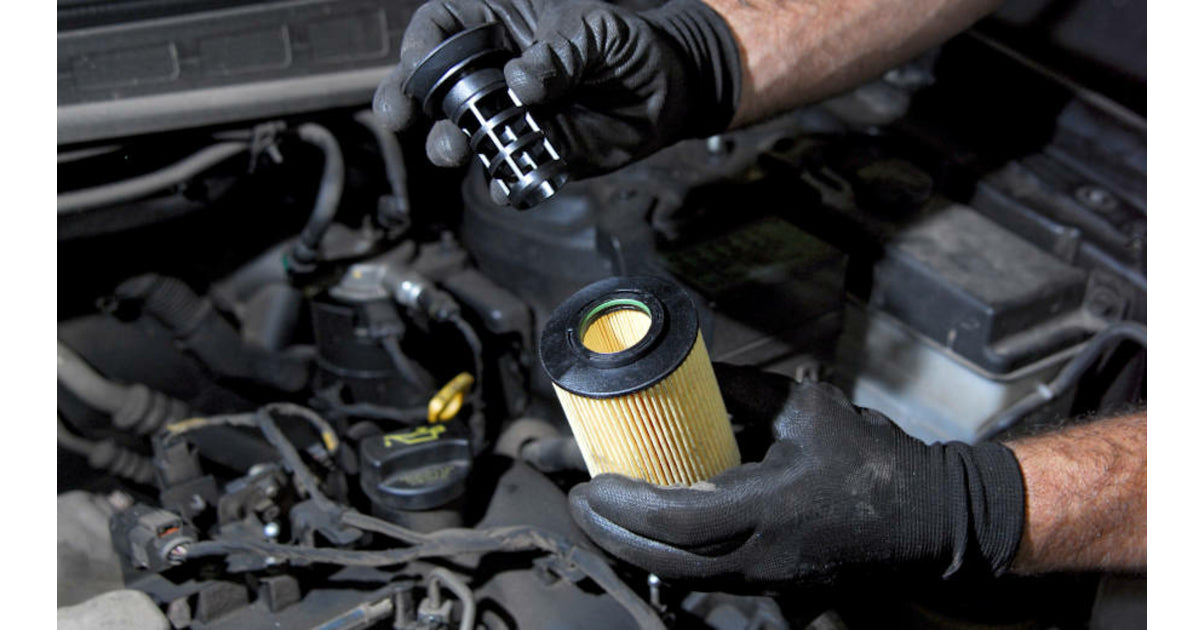 Mains gantées manipulant un filtre à huile et son support lors de la réparation d un moteur