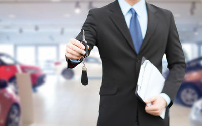 Conseiller en concession automobile tenant une clé de voiture pour un leasing