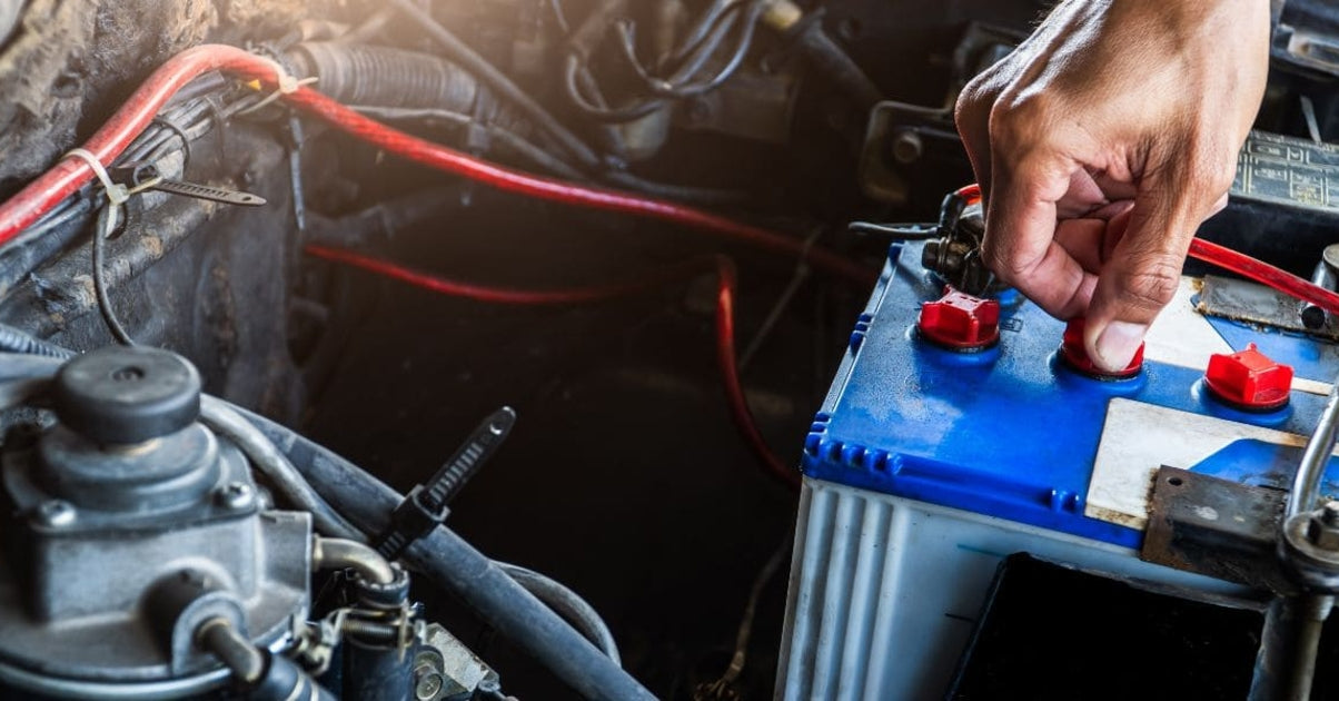 Main d'un mécanicien vérifiant les bouchons d'une batterie de voiture