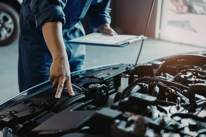 Un mecanicien inspecte le compartiment moteur d une voiture avec sa fiche de diagnostic