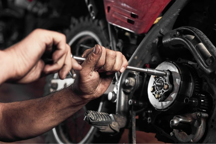 Mains d un mecanicien reparant l embrayage d une moto avant le controle technique
