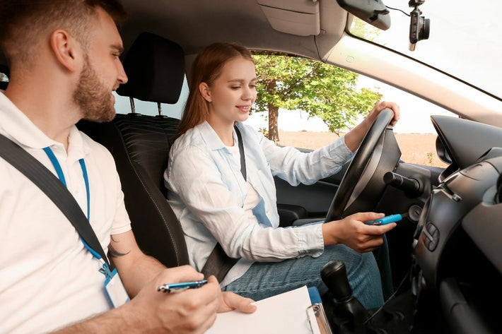 Jeune femme en leçon de conduite accompagnée insérant la clé de contact à côté de son moniteur