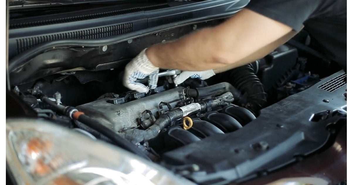 Mécanicien avec gants de protection réparant le moteur d une voiture avec capot ouvert