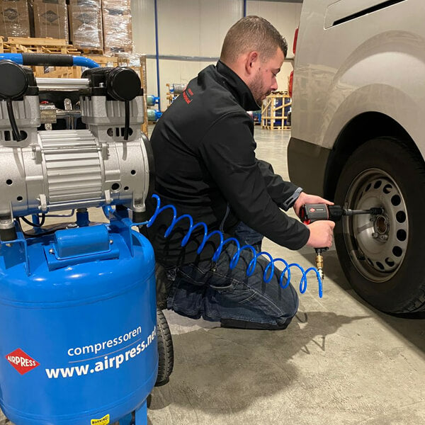 Technicien utilisant un outil pneumatique relié à un compresseur Airpress pour démonter une roue