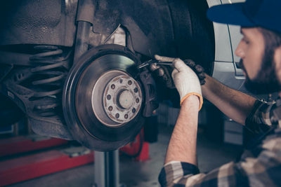 Meccanicien qui inspecte et mesure l usure des plaquettes de frein d une voiture