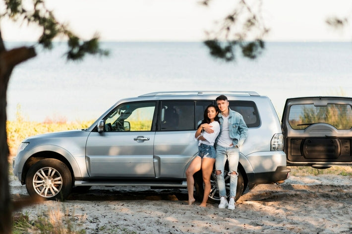 Couple posant devant un 4x4 argenté lors d un voyage au bord de l eau