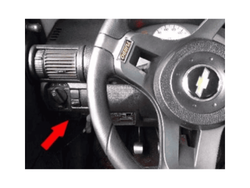 Flèche rouge indiquant l'emplacement de la boîte à fusibles sous le tableau de bord d'une Chevrolet Corsa Wind