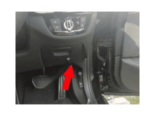 Une flèche rouge indique l'emplacement de la prise OBD sous le tableau de bord d'une BMW Série 5 G30 G31