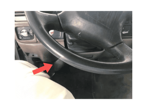 Fleche rouge indiquant l emplacement de la prise OBD sous le volant d un Chevrolet Suburban