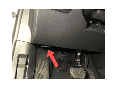 Une flèche rouge indique l'emplacement de la prise OBD2 sous le tableau de bord d'une Citroën C3 Aircross