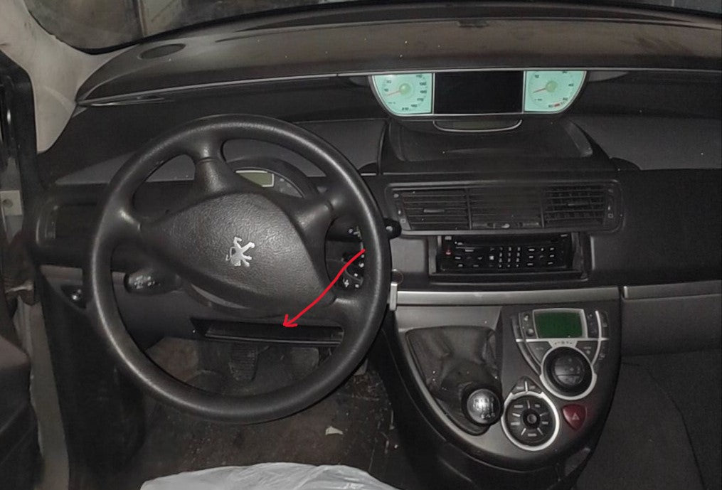 Fleche rouge indiquant l emplacement de la prise de diagnostic OBD2 sous le volant d une Peugeot 807