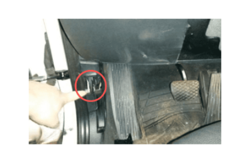 Doigt pointant vers l'emplacement de la prise de diagnostic OBD2 sur une BMW X1