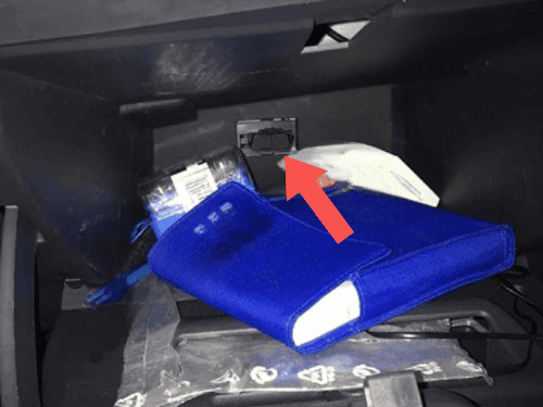 Flèche rouge montrant l emplacement de la prise OBD pour diagnostic dans la boîte à gants d une Dacia Logan 2