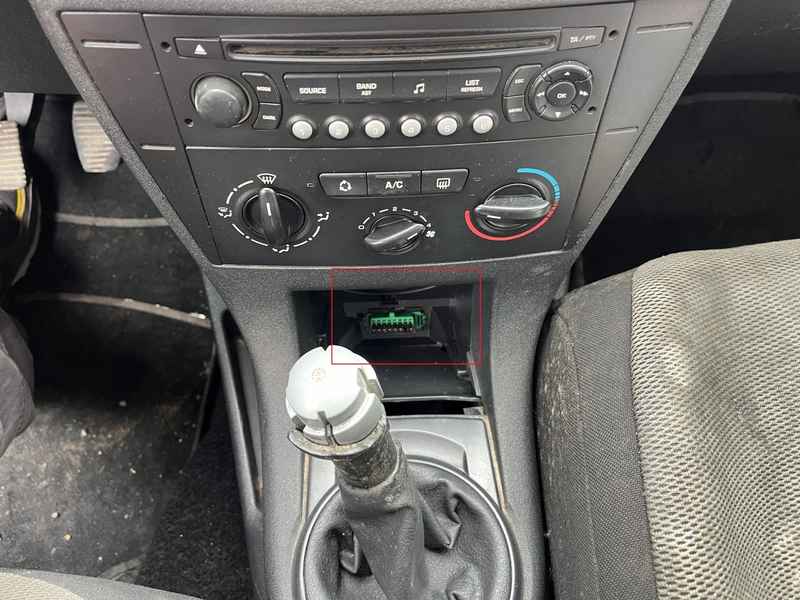 Emplacement de la prise OBD2 verte sur une Citroën C4 Coupé sous la console centrale