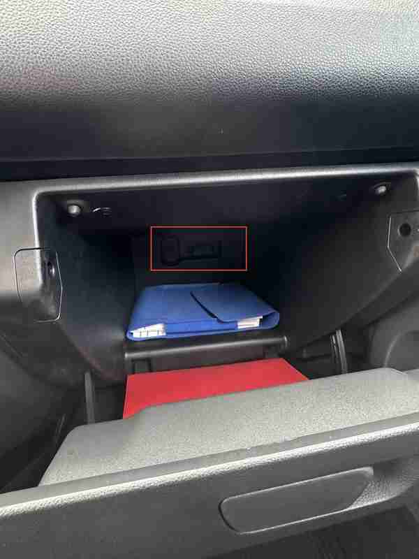 Emplacement de la prise OBD2 encadrée en rouge au fond de la boîte à gants d'une Dacia Spring