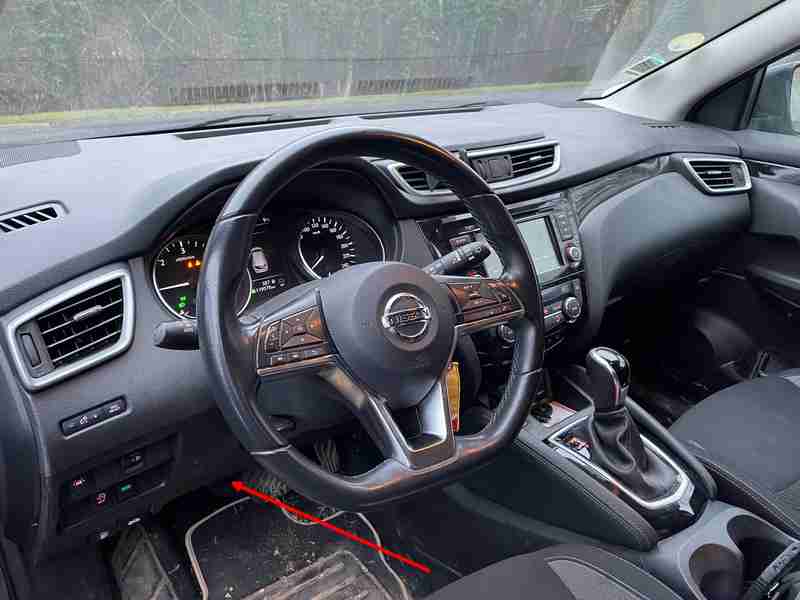 Une fleche rouge montre l emplacement de la prise OBD de diagnostic sur une Nissan Qashqai