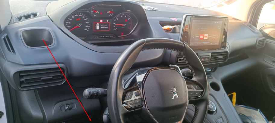 Vue de l habitacle d un Peugeot Rifter avec flèche rouge pointant sous le volant