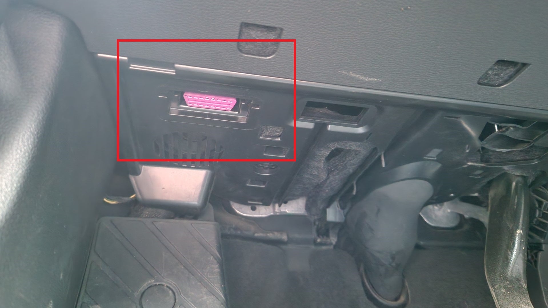 Visualisation de l'emplacement de la prise OBD rose sous le tableau de bord