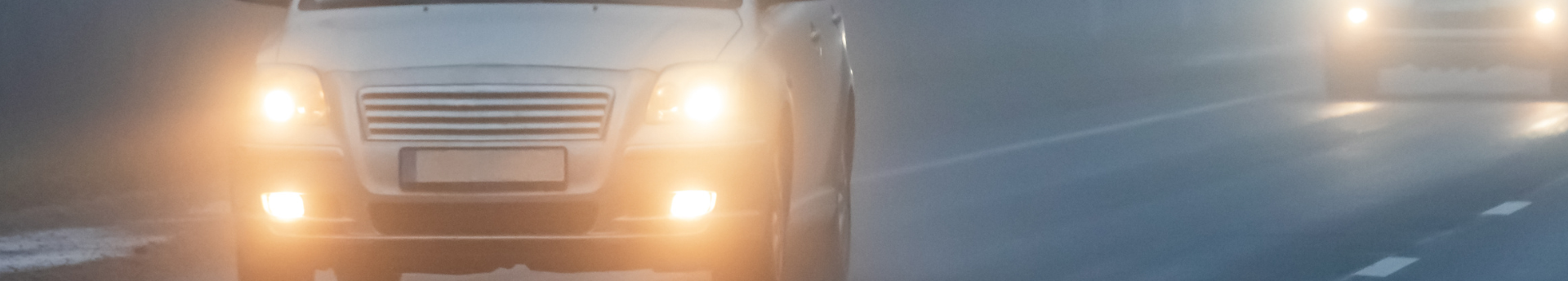 Voiture roulant dans le brouillard épais avec ses phares et feux de brouillard allumés