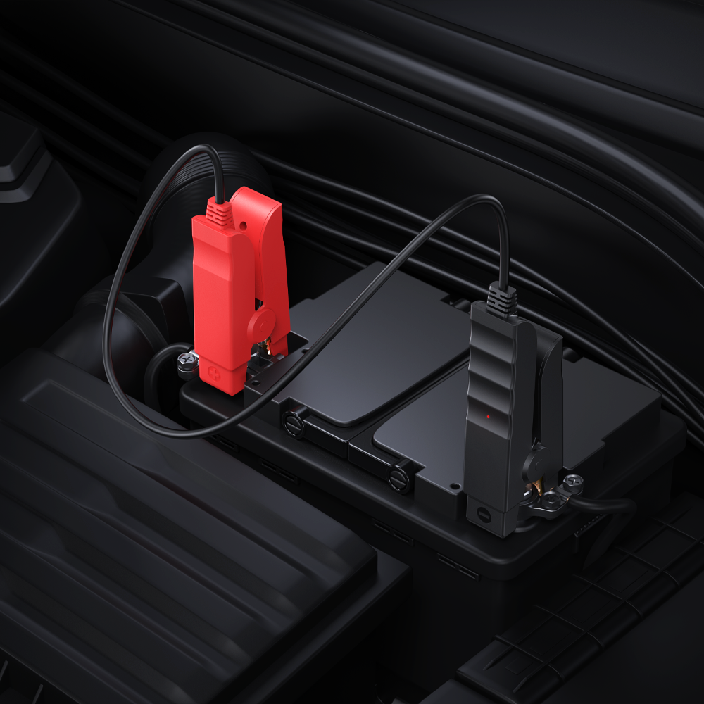 Pinces de démarrage rouge et noire branchées sur les cosses d'une batterie de voiture