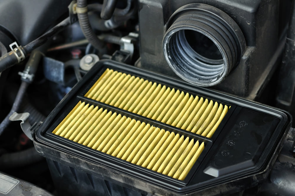 Filtre à air moteur jaune installé dans sa boîte sous le capot d une voiture
