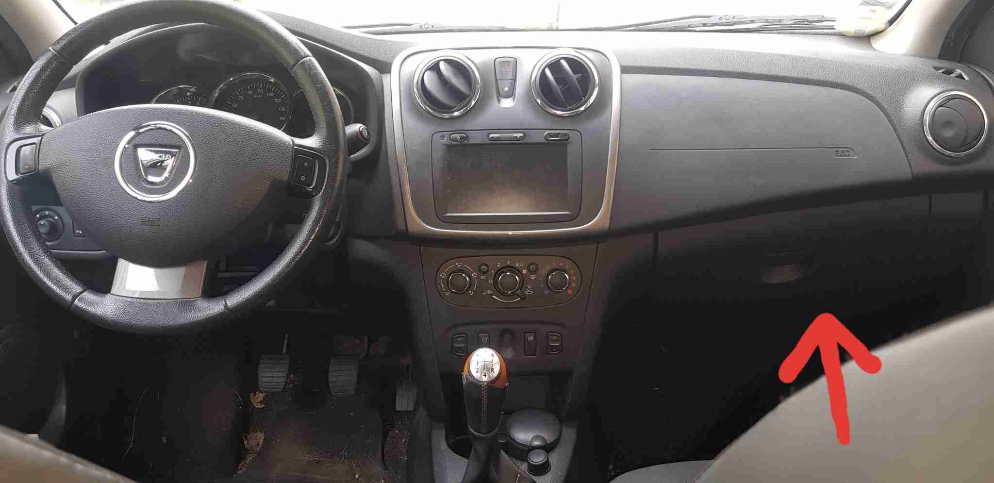 Habitacle dune Dacia Sandero Stepway montrant la boîte à gants désignée par une flèche