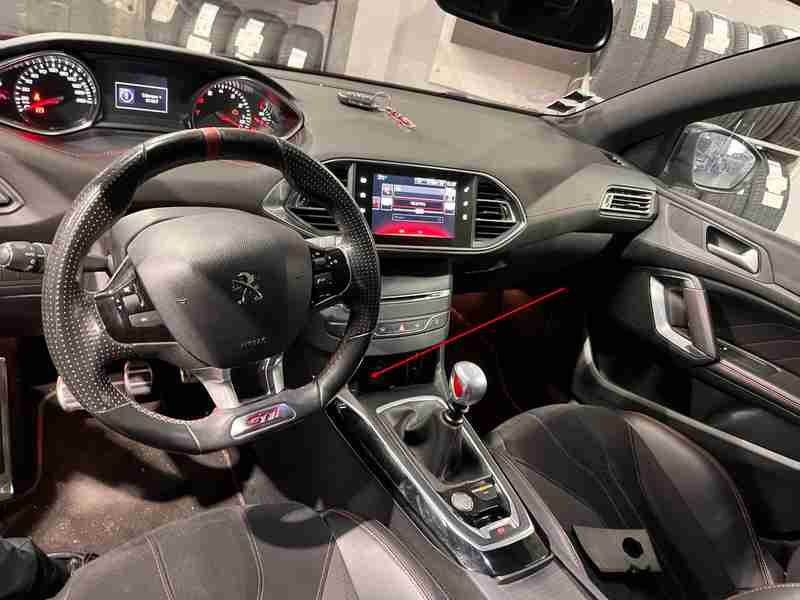 Vue intérieure de l'habitacle d'une Peugeot 308 GTi montrant le volant sport et la console centrale
