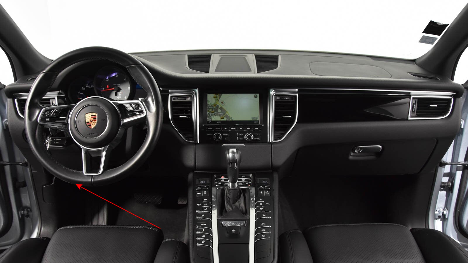 Vue de l habitacle d une Porsche Macan avec fleche rouge indiquant la zone de la prise de diagnostic OBD