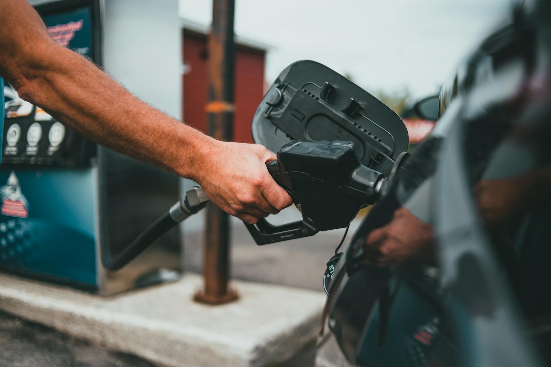Gros plan sur une personne qui fait le plein de carburant avec un pistolet essence dans un réservoir de voiture