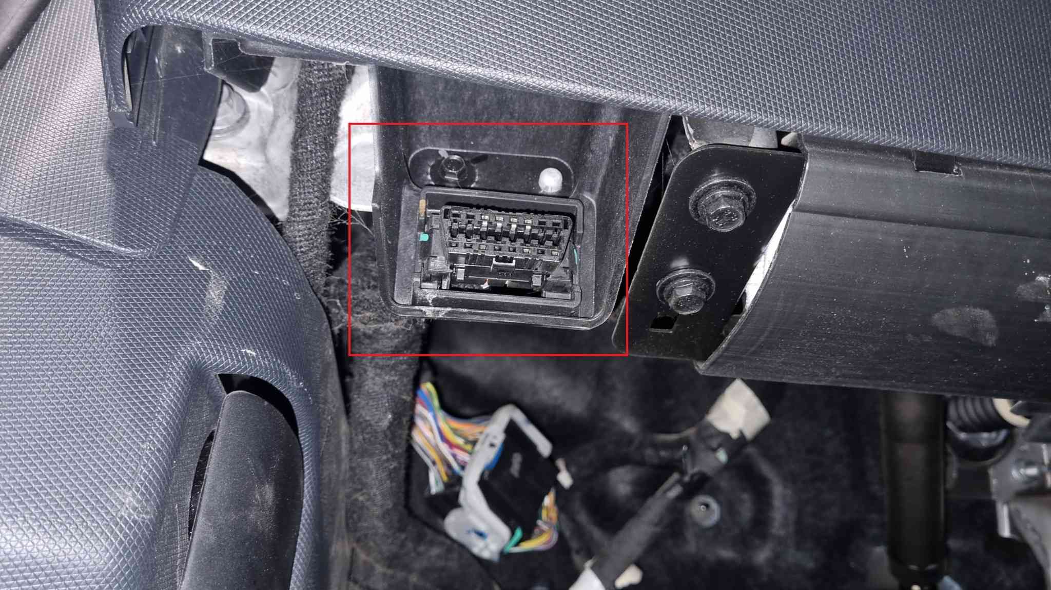 Emplacement de la prise OBD2 encadrée en rouge sous le tableau de bord d une Ford Mustang Mach-E