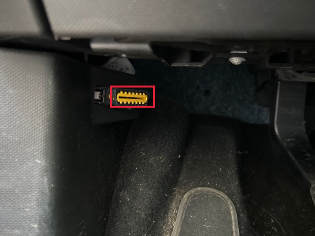 Port de diagnostic OBD2 jaune situé sous le tableau de bord côté conducteur