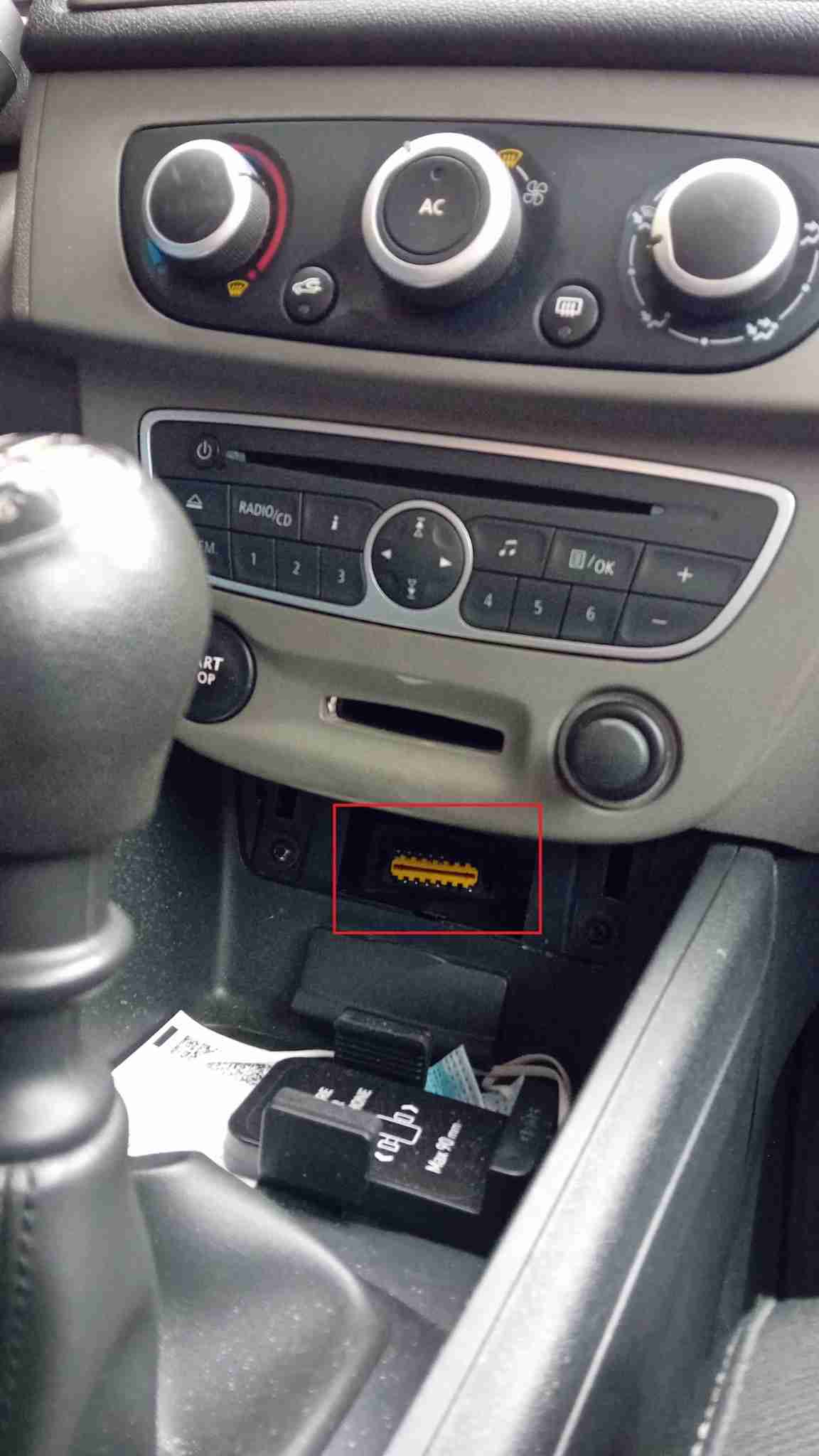 Emplacement de la prise de diagnostic OBD2 jaune sur une Renault Megane 3 sous la console centrale