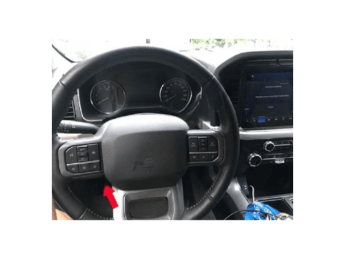 Gros plan sur le volant et le tableau de bord d'un pick-up Ford F150 avec une fleche rouge